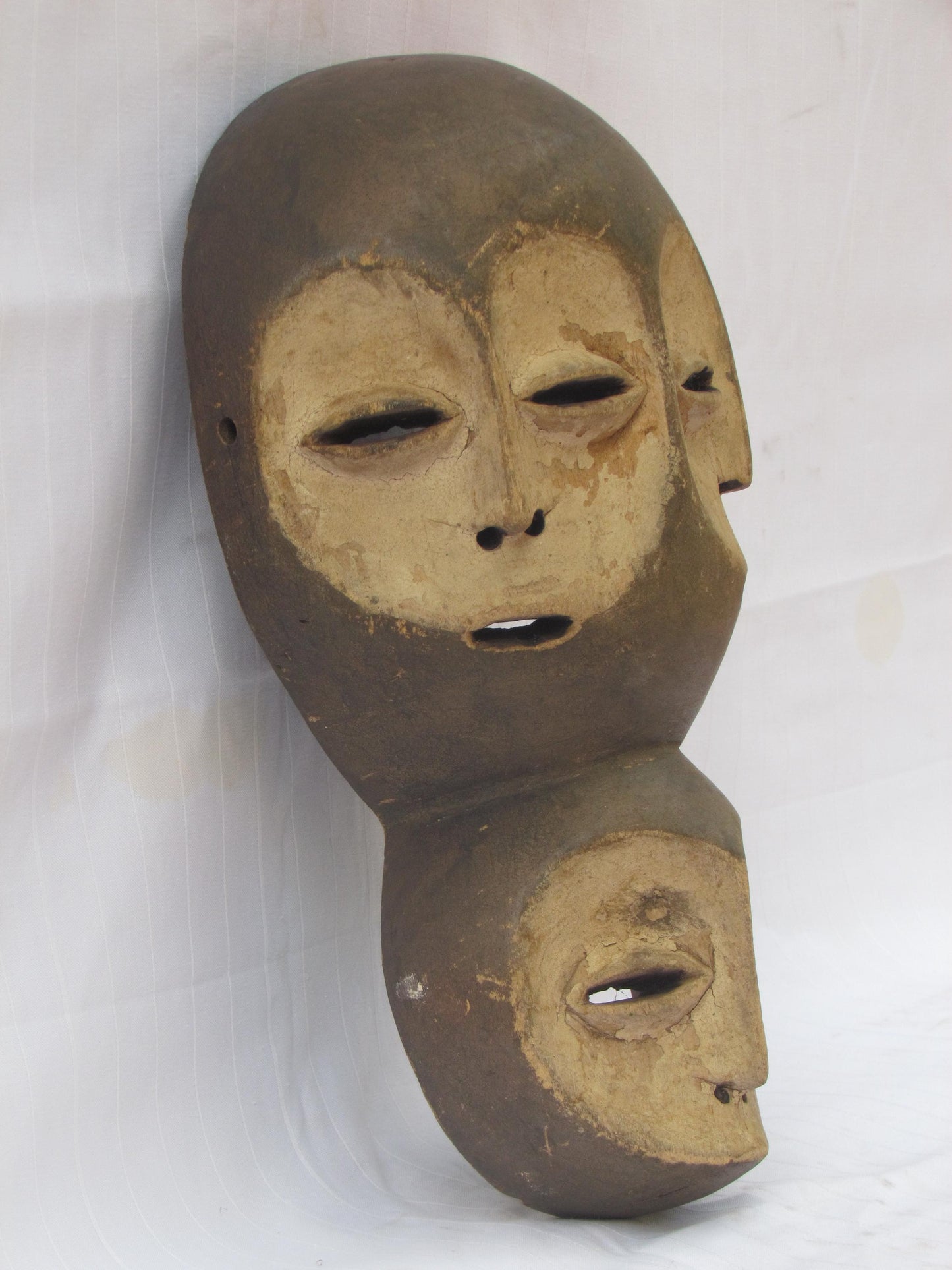 Un masque mural traditionnel africain en bois sculpté à la main à plusieurs visages de la RDC