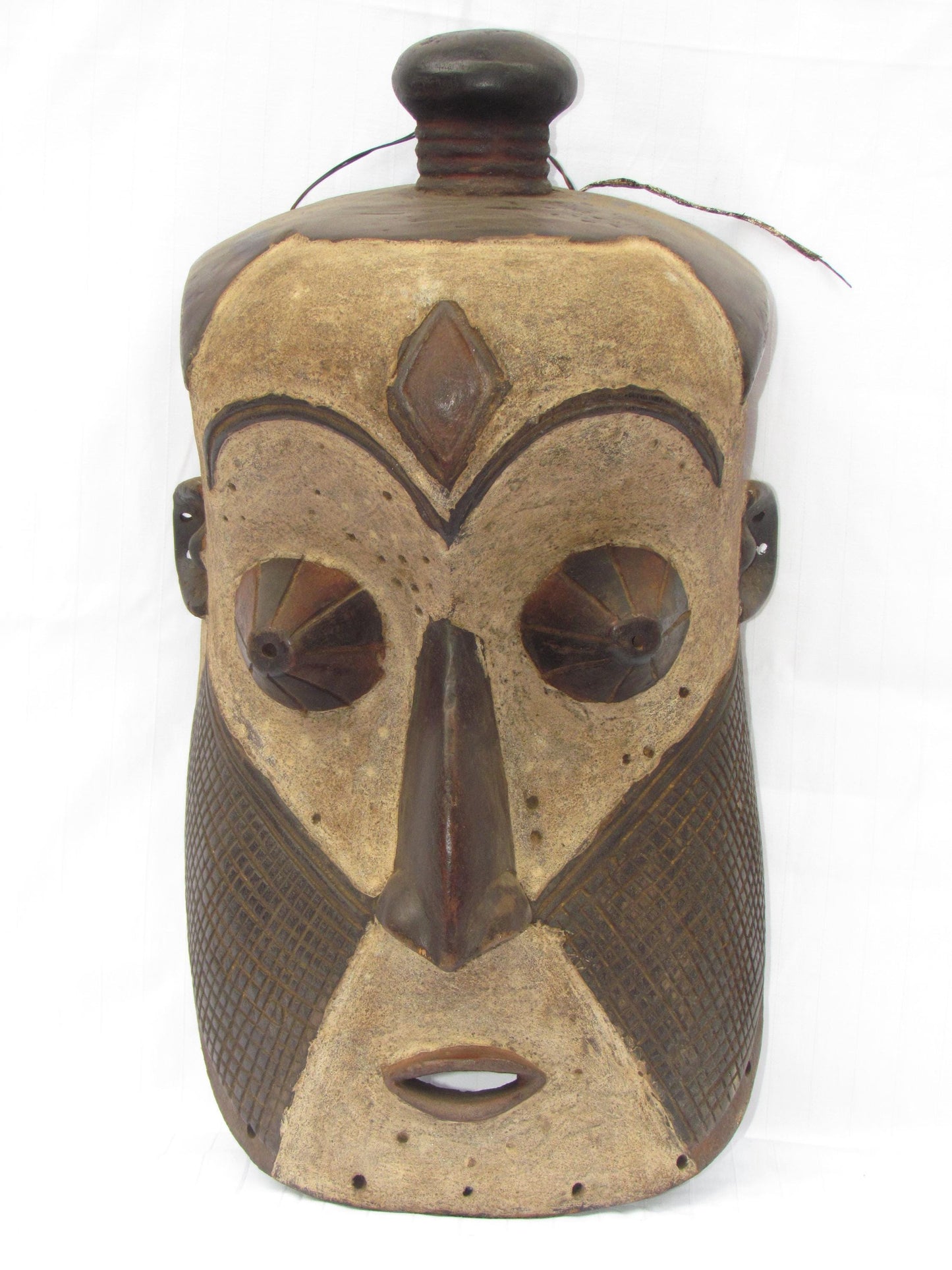 Un masque mural traditionnel africain en bois sculpté à la main de couleur marron, de la RDC