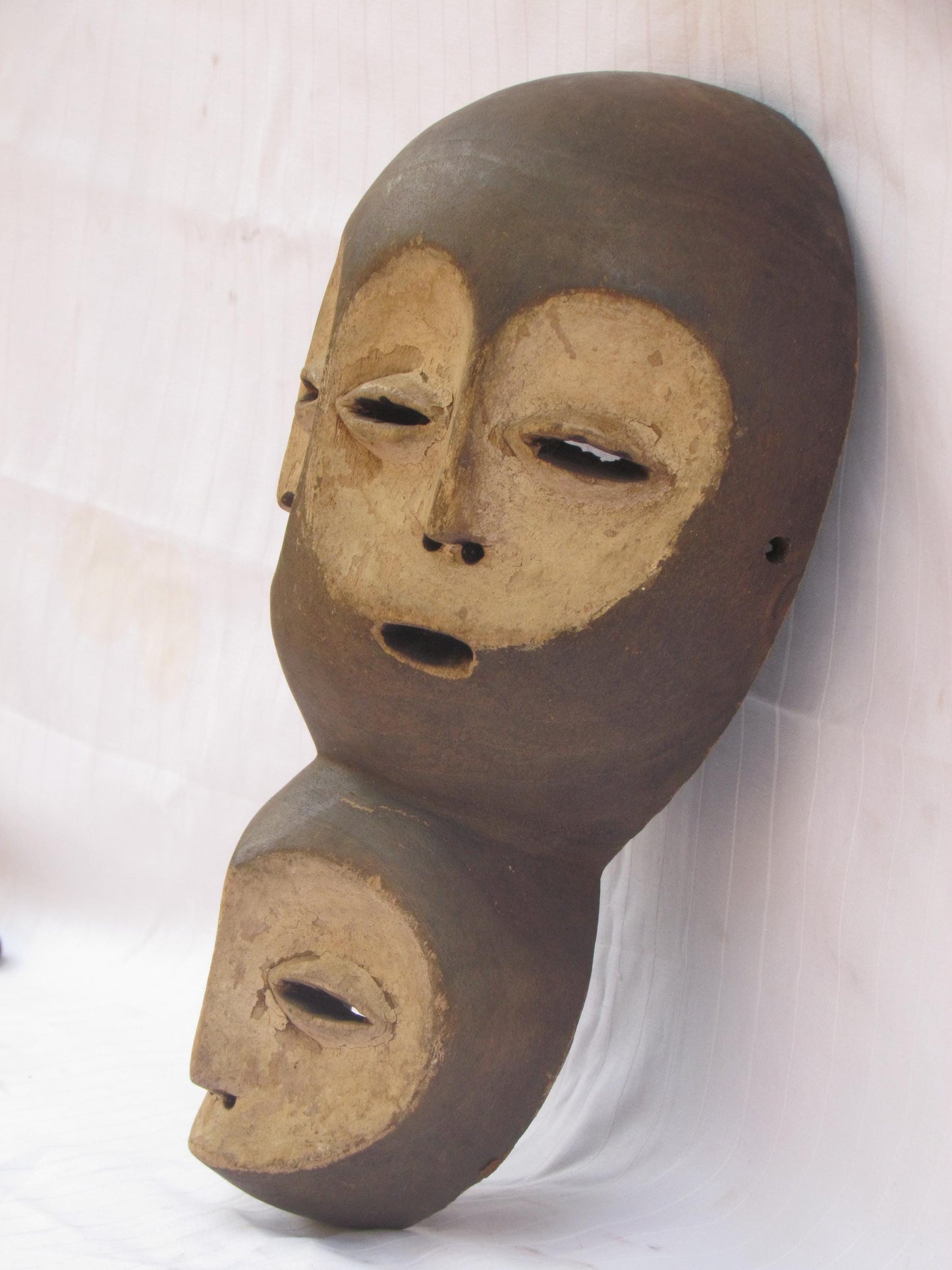 Un masque mural traditionnel africain en bois sculpté à la main à plusieurs visages de la RDC