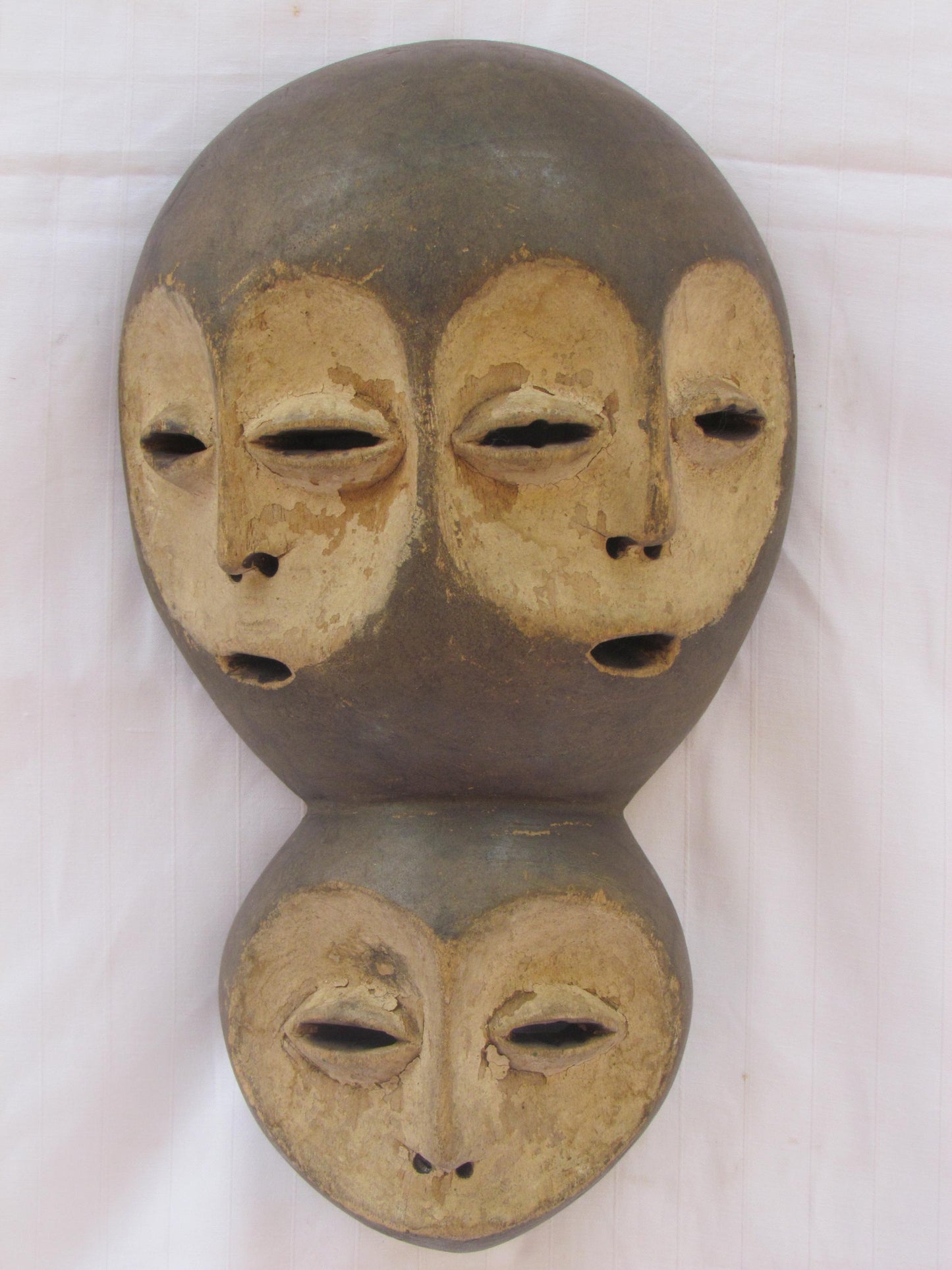 Un masque mural traditionnel africain en bois sculpté à la main à plusieurs visages de la RDC