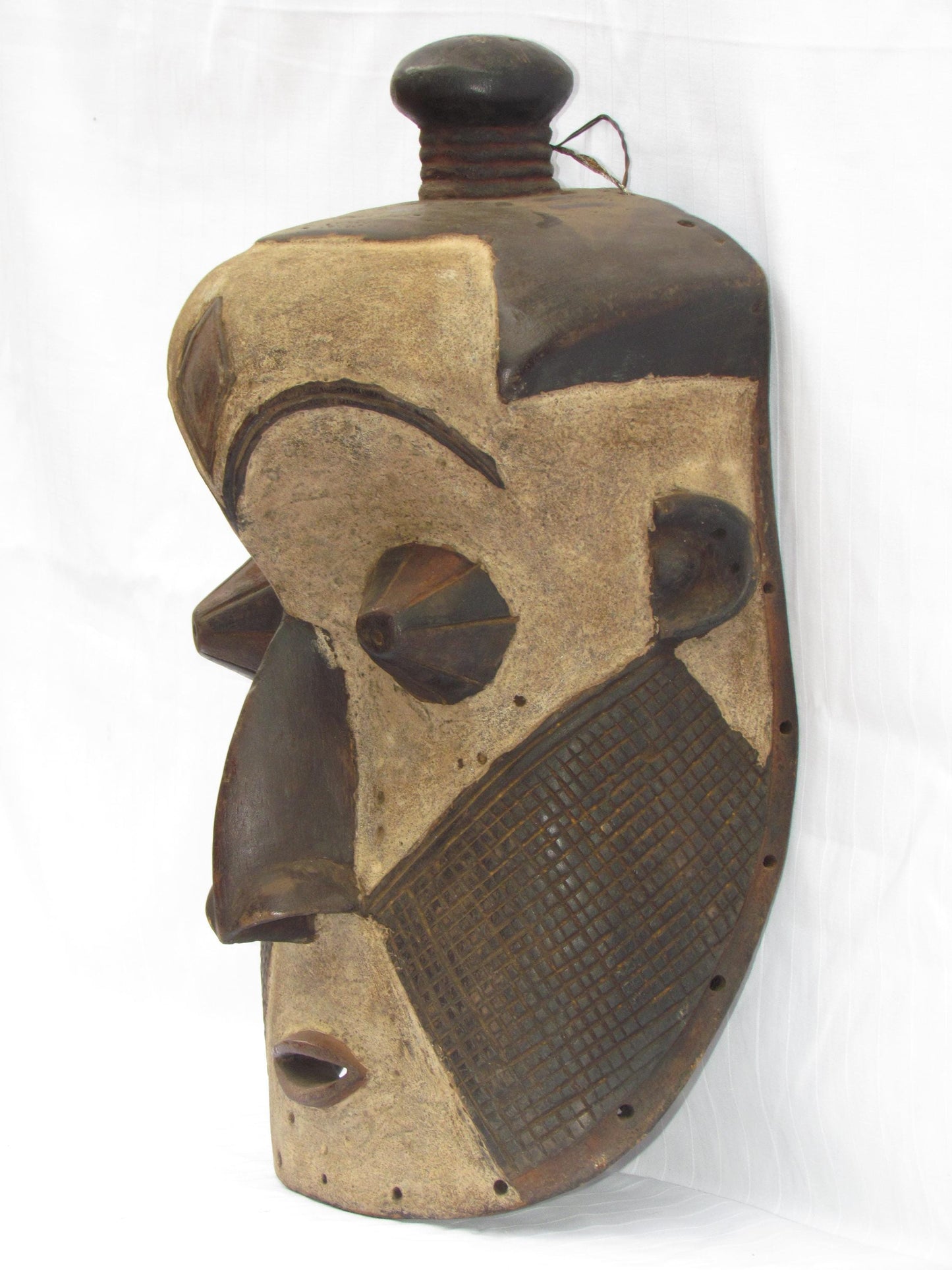 Un masque mural traditionnel africain en bois sculpté à la main de couleur marron, de la RDC