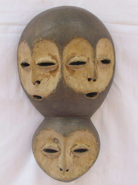 Un masque mural traditionnel africain en bois sculpté à la main à plusieurs visages de la RDC