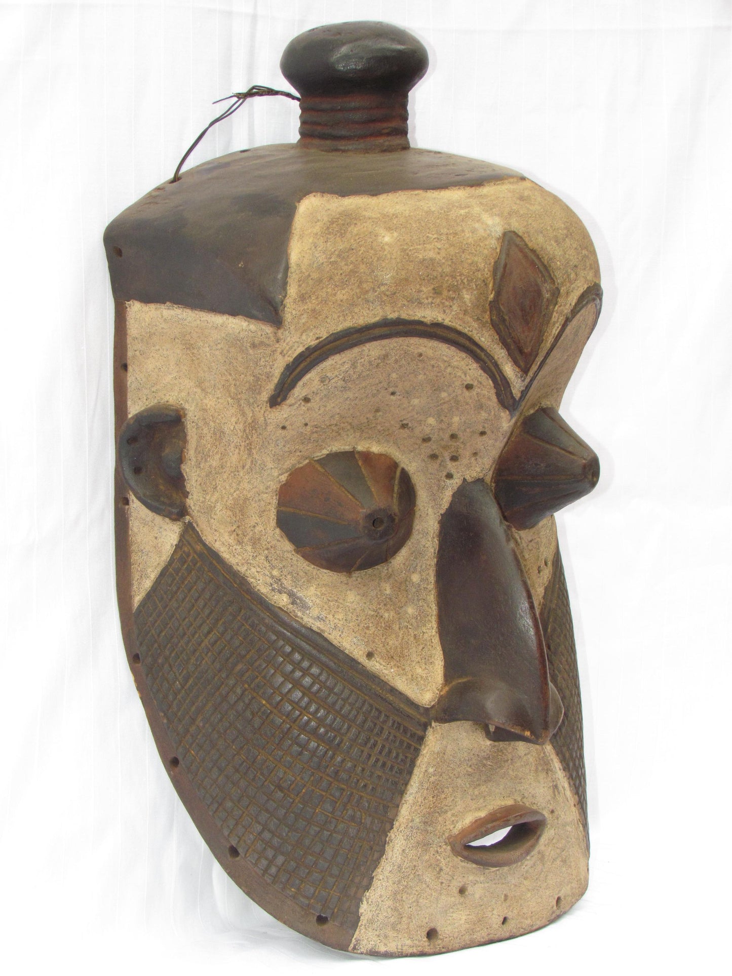 Un masque mural traditionnel africain en bois sculpté à la main de couleur marron, de la RDC